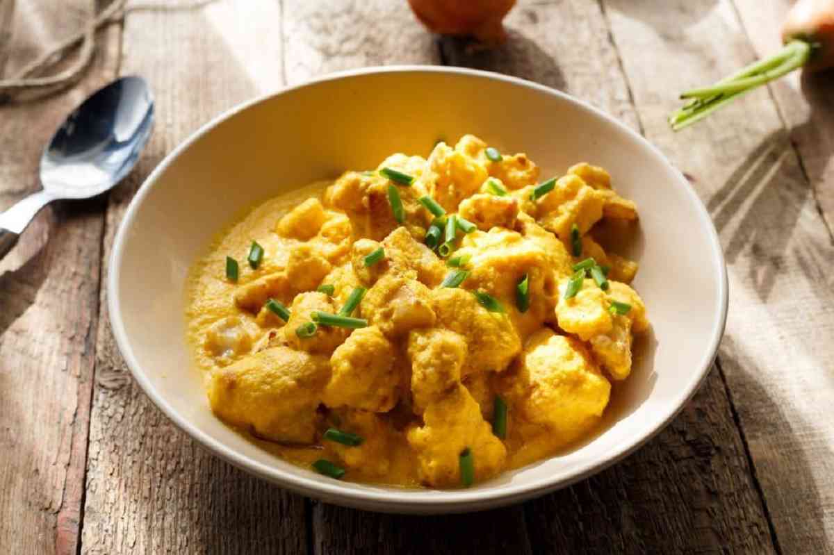 A plate of Mary Berry's Coronation Chicken, garnished with almonds and fresh cilantro.